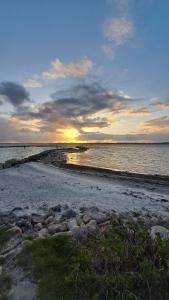 ein Sonnenuntergang über einem Strand mit Felsen und dem Meer in der Unterkunft Ferienwohnung Fördeblick in Schausende