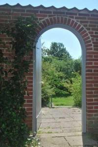 an archway in a brick wall with an open door at Gästehaus Rohde in Rothenhaus