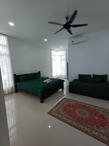 a living room with two beds and a ceiling fan at Mengkuang Villa, Penarik in Setiu