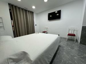 a bedroom with a large white bed and two chairs at Hotel Madrid Río in Madrid