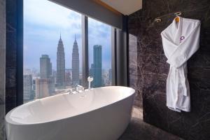 a bath tub in a bathroom with a view of the city at Atelier KLCC in Kuala Lumpur +43 photos