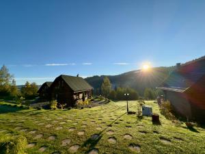 a house in a field with the sun setting behind it at Domki w górach '' Zielone Wzgórza '' okolice Karpacza in Karpacz