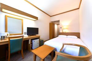 a hotel room with a bed and a desk and a computer at Daiichi Inn Ikebukuro in Tokyo