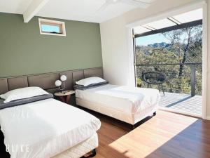 卢拉The Mountain View Cottage in Leura的一间有两张床和一扇大窗户的卧室