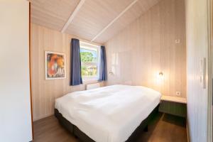 a bedroom with a large white bed with a window at Strandblick - Dorf 1 Ferienhaus 09 in Priwall