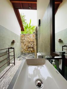 un bagno con una grande vasca bianca con finestra di Mango Tree House a Udawalawe