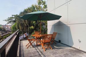 a table and chairs with a green umbrella on a balcony at Urbanview Greenville Jakarta in Jakarta