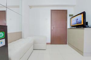 a living room with a couch and a flat screen tv at Homey and Modern 2BR at Loftvilles City Apartment By Travelio in Tangerang