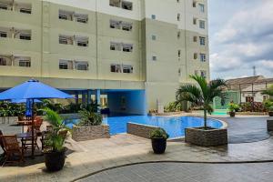 a hotel with a pool in front of a building at Homey and Modern 2BR at Loftvilles City Apartment By Travelio in Tangerang
