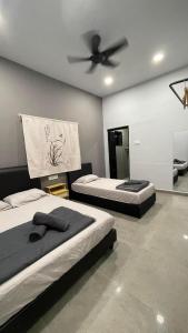 a bedroom with two beds and a ceiling fan at Sam Choon Homestay 三春客棧 Batu Pahat City Centre 4R4B4CP 峇株巴轄民宿 市中心Summit旁邊 四房四浴停車方便 in Batu Pahat
