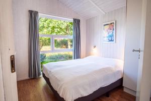 a bedroom with a bed and a large window at Strandblick - Dorf 1 Ferienhaus 07 in Priwall