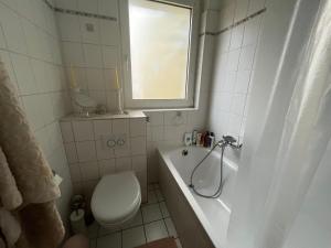 a bathroom with a toilet and a tub and a window at Feel home Room in Frankfurt/Main