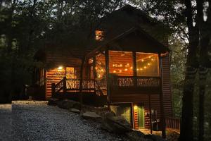a cabin in the woods at night with lights at Tree Top Hideaway - Private with Games Firepit More in Blue Ridge