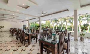 a restaurant with tables and chairs and palm trees at Treebo Tiger Pug Mark Resort with Pool in Rāmnagar