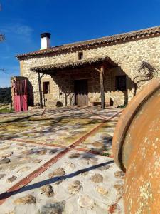 ein altes Steingebäude mit einem großen Gebäude in der Unterkunft Agroturismo Los Prados Sierra de San Vicente in Castillo de Bayuela