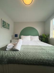 a bedroom with a large bed with a green headboard at Serenity & Style With Parking in Lombard