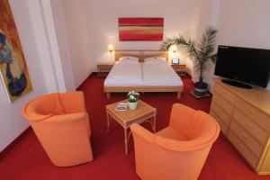 a room with a bed and two chairs and a tv at Hotel Haus Bismarck in Berlin