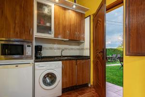 eine Küche mit Waschmaschine und Mikrowelle in der Unterkunft Apto Amarillo - Casa el gaitero in Susacasa