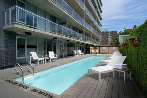 a swimming pool with white chairs and a building at SOHO Residences Lisgar in Ottawa