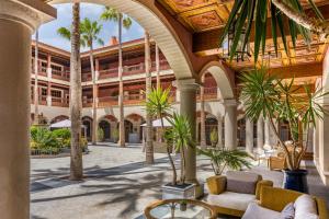 an indoor courtyard with palm trees and a building at Elba Palace Golf Boutique Hotel - Adults Only in Caleta De Fuste