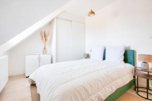 a white bedroom with a large bed and a staircase at Centre-ville Pléneuf Val André, appartement pour 4 in Pléneuf-Val-André