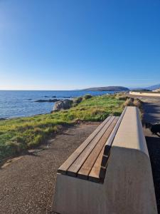 a wooden bench sitting on a path near the ocean at Cumbrae Loft in Millport