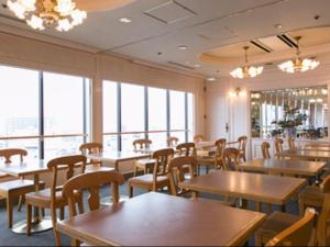 ein Esszimmer mit Tischen und Stühlen und Fenstern in der Unterkunft Takamatsu Washington Hotel Plaza in Takamatsu