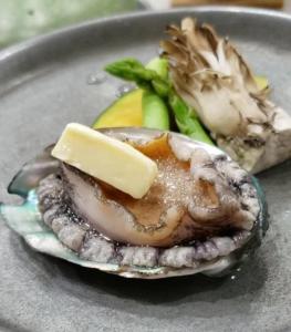 a oyster with cheese and vegetables on a plate at Hotel Saiyou WAKIGAWA in Hirado