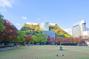 a park with trees on a hill with buildings at KKR Hotel Hakata in Susakiuramachi