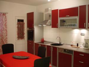 a kitchen with red cabinets and a red table and chairs at House Boris in Slatine
