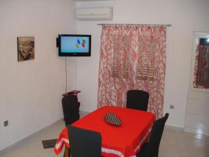 a dining room with a red table and a tv on the wall at House Boris in Slatine