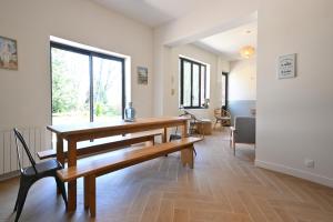 a dining room with a wooden table and a large window at Maison dans un cadre bucolique in Longuenesse