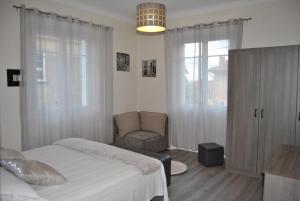 ein Schlafzimmer mit einem Bett, einem Stuhl und einem Fenster in der Unterkunft Le Calme au Centre Ville à 10 minutes à pied de la Croisette et des plages in Cannes