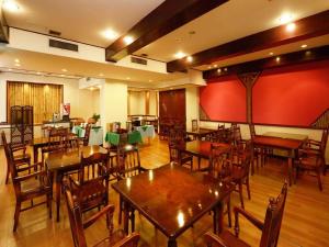 上田市Ueda Plaza Hotel的餐厅设有木桌和椅子,拥有红色的墙壁