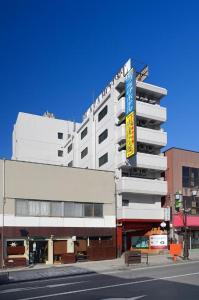 上田市Ueda Plaza Hotel的一栋白色建筑，侧面有一块招牌