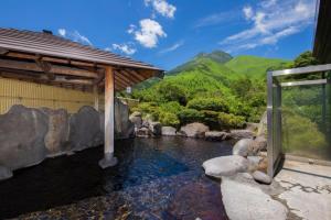 una piscina d'acqua accanto a un edificio con torrente di Yufuin Onsen Yufuin Nanairo no Kaze a Yufu