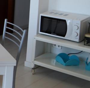 a microwave oven sitting on a shelf with a chair at Kaary Bella Vista in Marina di Ragusa