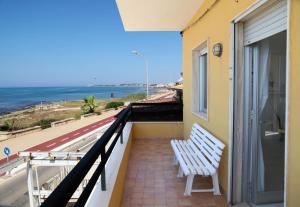 a white bench sitting on a balcony overlooking the ocean at Kaary Bella Vista in Marina di Ragusa