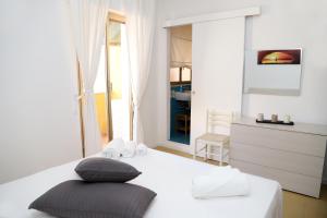 a white bedroom with a bed with two pillows at Kaary Bella Vista in Marina di Ragusa