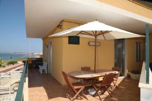 a table and chairs with an umbrella on a balcony at Kaary Bella Vista in Marina di Ragusa