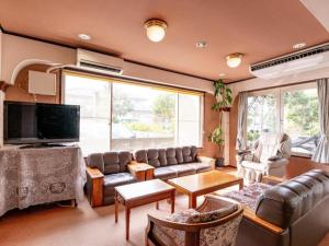 a living room with a couch and a tv at Tabist Hotel Sankoen in Hitachi