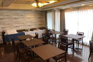 a dining room with wooden tables and chairs and a room with a tableablish at Tabist City Hotel Higashi-Matsuyama in Higashimatsuyama