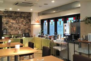 a restaurant with wooden tables and a stone wall at Matsumoto Wellton Hotel in Koyanagichō