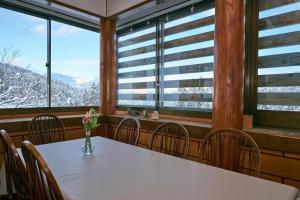 a dining room with a table and chairs and windows at Saint Moritz Ichibankan in Yuzawa