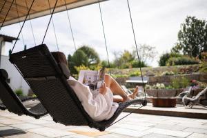 a woman sitting in a swing reading a magazine at Hotel Johanneshof in Oberstaufen