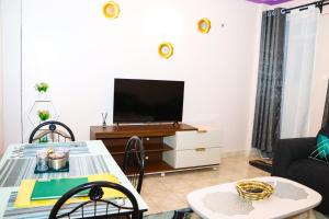 a living room with a tv and a table at Texas Homes Meru 1 and 2 Bedroom Apartments in Meru
