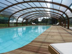 an indoor swimming pool with an arched roof at Les Roulottes de la Risle in Calleville