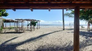 a beach with tables and umbrellas on the sand at Suítes na Beira do mar in Canavieiras