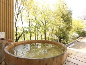 una bañera de madera llena de agua en una terraza en Yuzanso, en Otsu