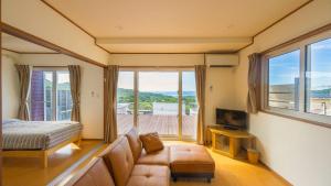 a living room with a couch and a bed and windows at セイントY saint-Y in Motobu
